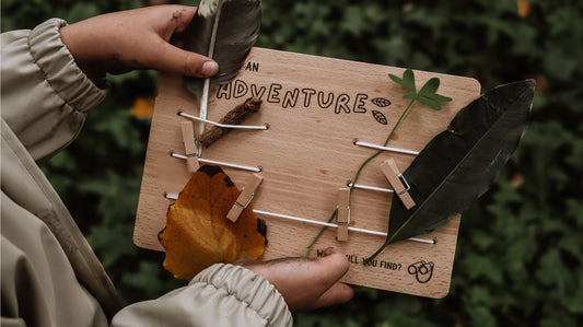Wooden board with nature-themed decorations held by a child outdoors. Kids nature board.